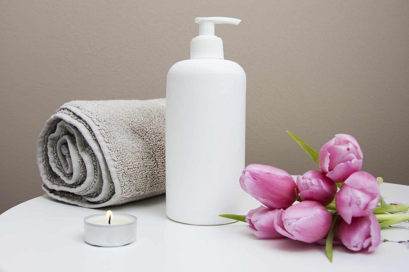 Amber glass massage oil bottles beside folded white towels and a sprig of eucalyptus on dark stone